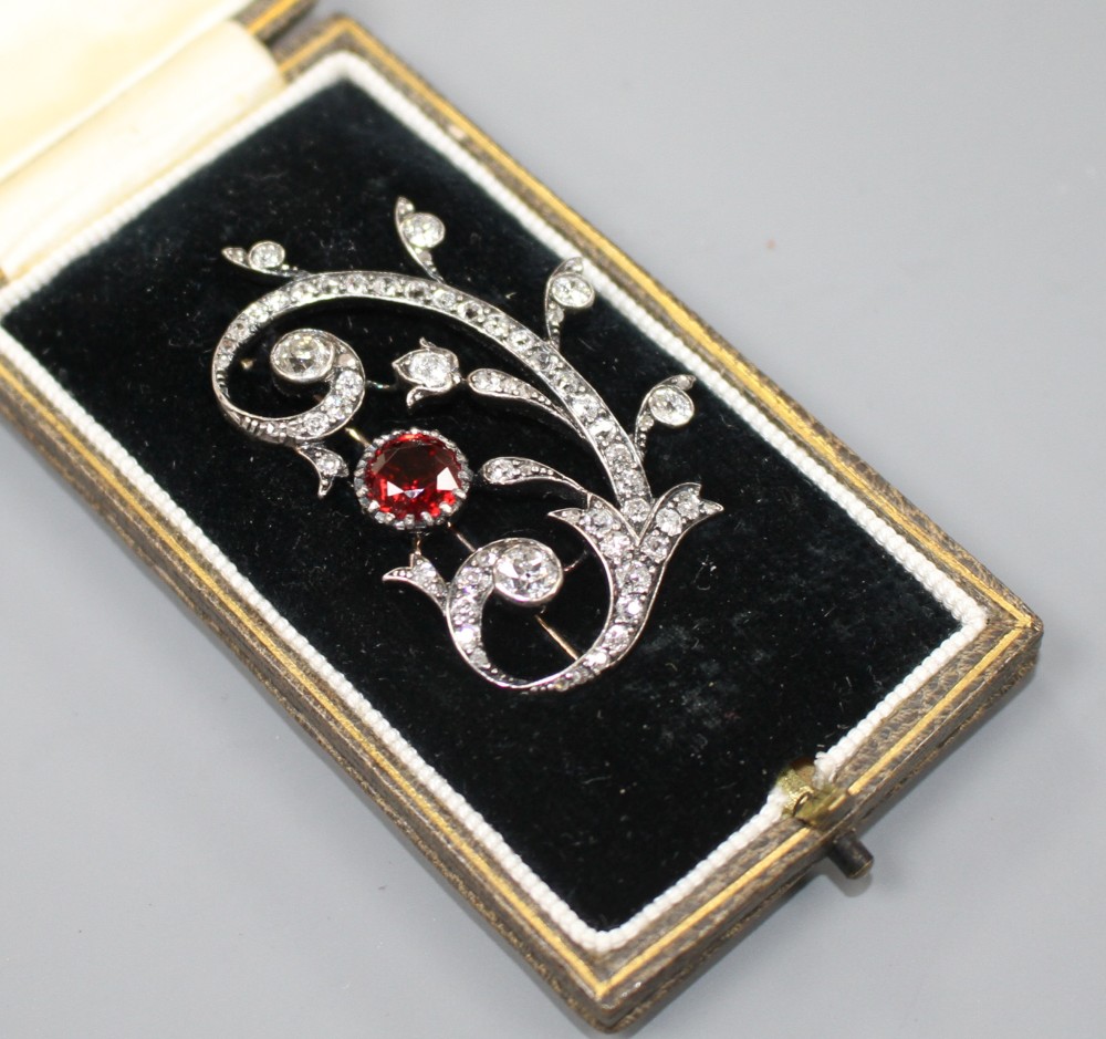 An early 20th century yellow and white metal, red spinel and diamond set foliate scroll brooch,